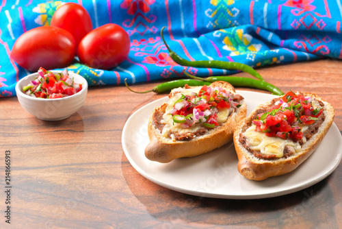 Bild auf Leinwand Close up of delicious molletes with pico de gallo salsa, whole tomatoes, and gre