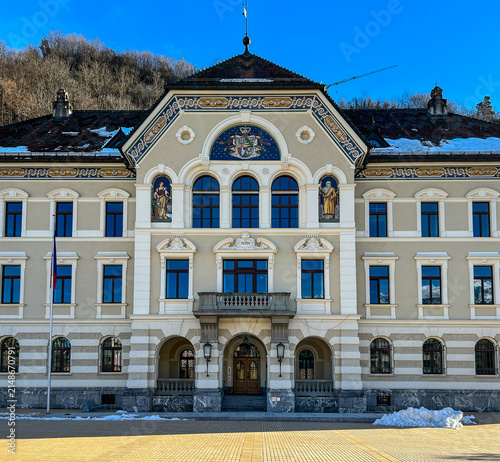 View of the historic Government Building with its ornate facade and central coat of arms under a clear blue sky in Vaduz, Liechtenstein.
