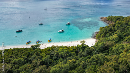 Aerial view of Whitehaven Beach featuring turquoise waters, white sand, and several boats anchored near the lush tropical forest in Whitsundays, Queensland, Australia.
