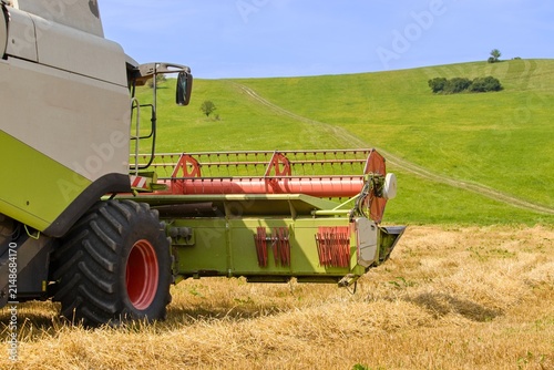 Combine harvester harvesting wheat in field on sunny day