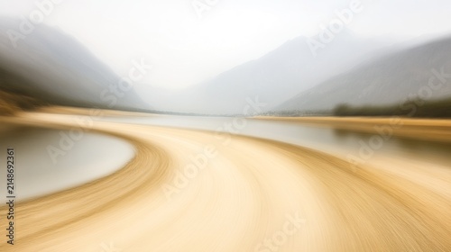 A sweeping curve of light beige sand along a still waterway, framed by misty mountains.