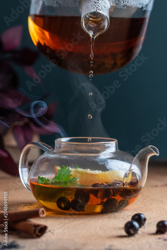 Glass teapot with herbal tea, berries and citrus under a drip brewer