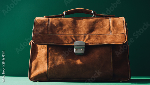 Classic brown leather briefcase on teal background.