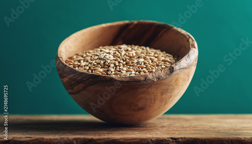 Rustic Wooden Bowl of Quinoa on Teal Background.