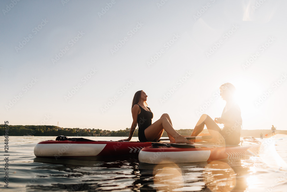Fototapeta premium Women relaxing on paddleboards at sunset