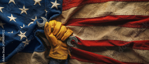 Worn work glove holding wrench on the American flag. Symbolic of hardworking blue collar workers, USA manufacturing, pride in products Made in United States of America, or to celebrate US Labor Day.