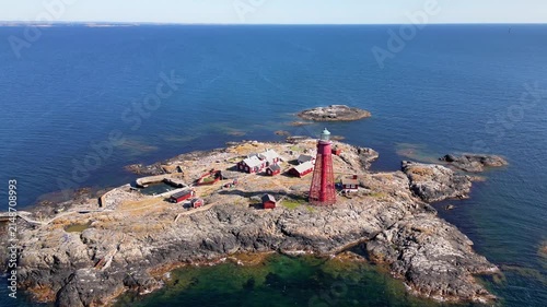 Aerial view of the iconic red Pater Noster Fyr lighthouse situated on a rugged, rocky island surrounded by the deep blue waters of the sea in Kladesholmen, Vastra Gotalands lan, Sweden.