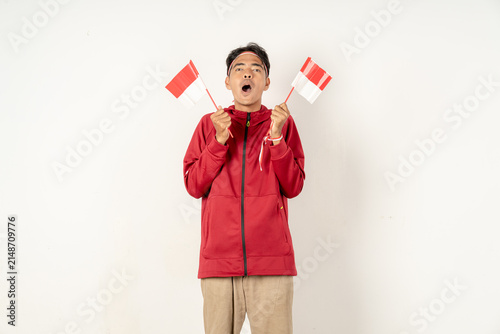 Foto Surprised Indonesian supporter holding two small national flags against white ba