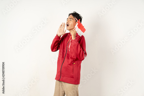 Photography Indonesian supporter shouting with hand near mouth holding small national flag