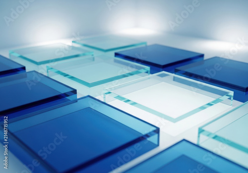 Grid of translucent glass squares in varying shades of blue resting on white surface creating modern architectural pattern with soft light reflections.