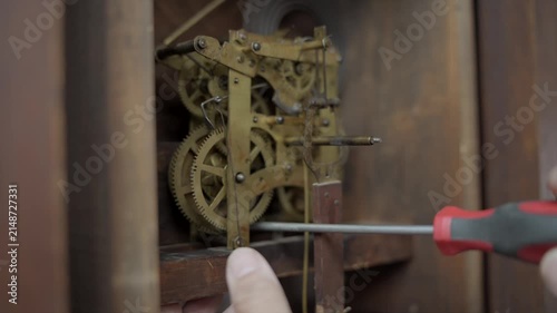Extreme close up macro shot of a watchmaker using a precision screwdriver to delicately adjust the brass gears and internal mechanical parts of an antique clock.