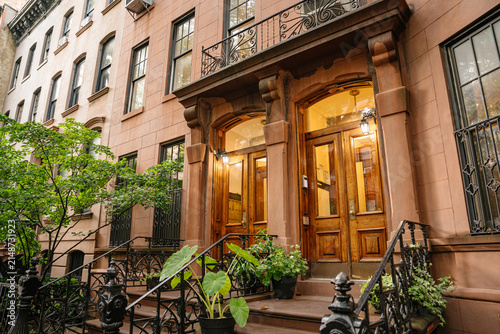 Canvastavla Vertical view of a historic New York brownstone facade featuring balcony details and warmly illuminated wooden doors
