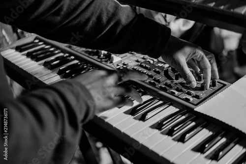 Photography Black and white close-up of a producer hands tweaking dials on a music synthesizer keyboard