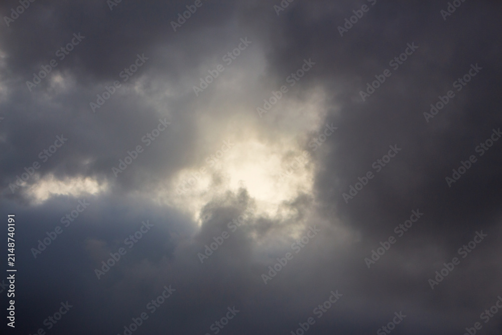 Obraz premium Dramatic Storm Clouds with Bright Sunlight Breaking Through, Dark Moody Sky and Atmospheric Weather Background