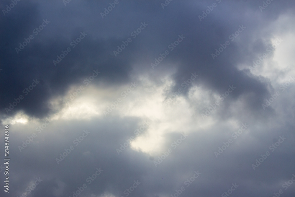 Obraz premium Dramatic storm clouds with bright light breakthrough, dark overcast sky texture, moody atmospheric weather background