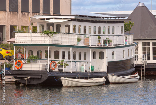 Traditional houseboat with small boats in Copenhagen harbor Denmark