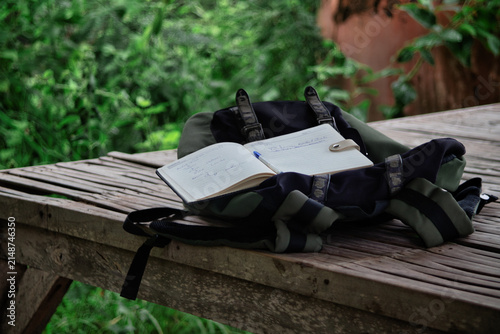 Open Travel Journal and Backpack on Wooden Table in Nature
