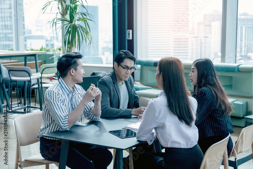 A group of Gen Z Asian business consulting, exchanging information in offices, co-working spaces.