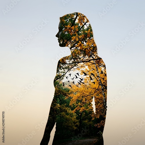 Woman silhouette filled with autumn forest trees.
