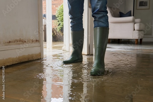 Person Wearing Rubber Boots Standing in a Flooded Home Interior During Heavy Rain