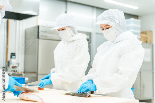 Photography Male and female staff in sanitary uniforms preparing fish (cooks, chefs, fresh f