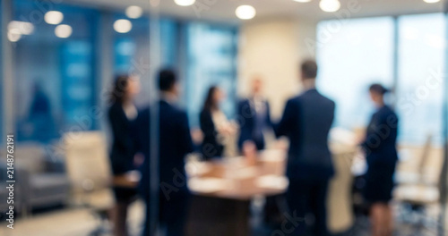 A group of business professionals engaged in a meeting in a modern office environment, blurry background emphasizing collaboration and discussion.