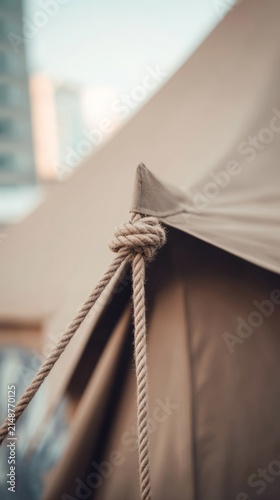 Close-up of taut triangular tent corner secured by rope.
