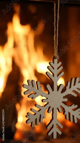 Wooden Snowflake Ornament Hanging in Front of a Warm Cozy Fireplace