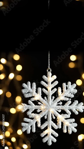 Glowing White Snowflake Christmas Ornament Hanging Against Blurred Golden Fairy Lights