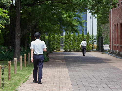真夏の昼の都市の街で歩くサラリーマンの姿
