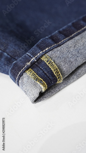 Macro Close Up View of Rolled Blue Denim Jeans Hem Seam with Yellow Stitching Detail