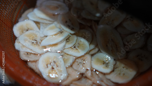 Cuadro en lienzo Detail of banana chips from a traditional banana cutter on orange bower filled o