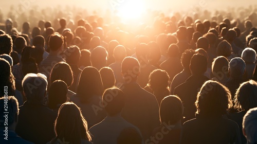 People standing in large crowd silhouetted by bright orange sunset light outdoors during golden hour