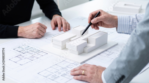 Professional architect presenting a modern building model to client during architectural planning meeting.