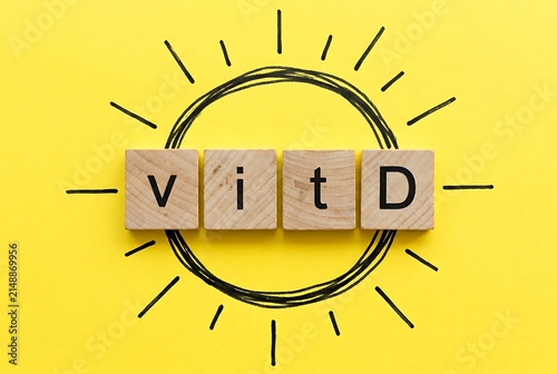 Wooden blocks spell out 'Vit D' within a hand-drawn sun, symbolizing health and wellness. Healthy Eating and Sunlight concept.