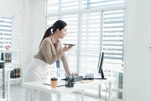 Young Businesswoman Working at Office Desk While Managing Documents and Mobile Communication.