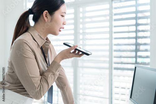 Young Businesswoman Working at Office Desk While Managing Documents and Mobile Communication.