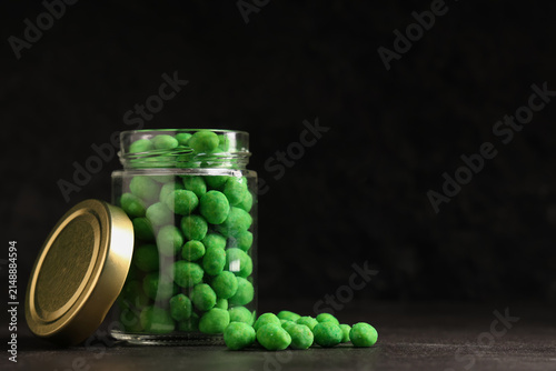 Obraz na plátne Jar with wasabi coated peanuts on black background