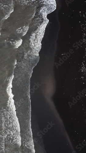 Ocean waves washing over black volcanic sand beach from directly overhead in Indonesia
