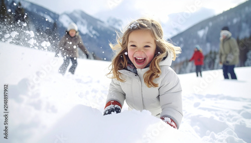 Joyful Little Girl Laughing and Playing in Fresh White Snow with Mountain Background in Winter