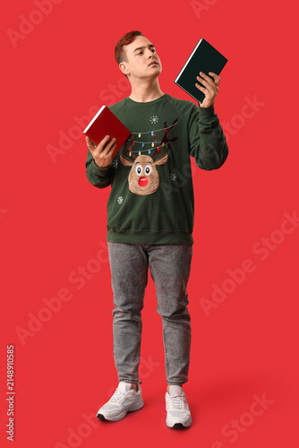 Thoughtful young man with books on red background