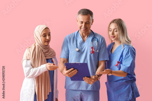 Professional team of doctors with red ribbons on pink background. World AIDS ...
