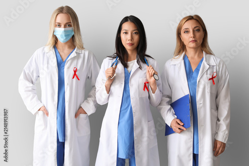 Professional team of doctors with red ribbons on grey background. World AIDS ...