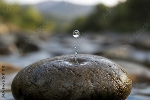 A single water drop persistently falling onto a stone, creating a visible indentation over time.