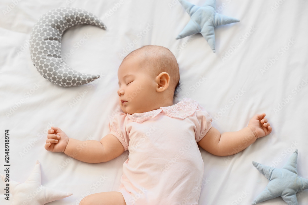 Obraz premium Little cute baby with toys sleeping on bed at home