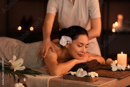 Young woman having massage in dark spa salon