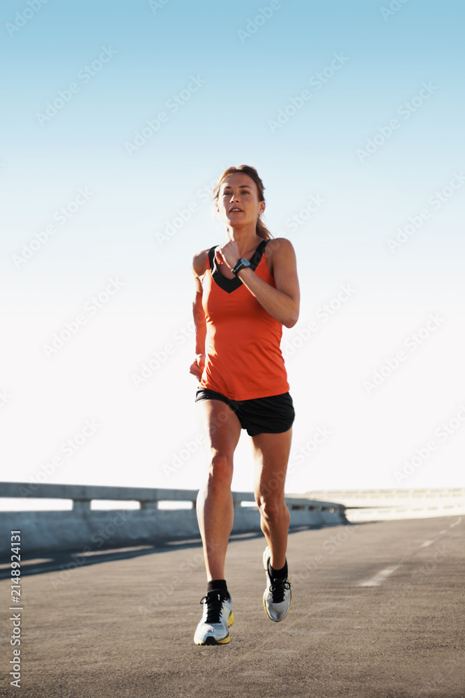 Obraz premium Fitness, woman and running exercise on bridge for workout challenge, athletic performance or health. Active, runner and sprint interval training on highway road for speed, stamina or pace improvement