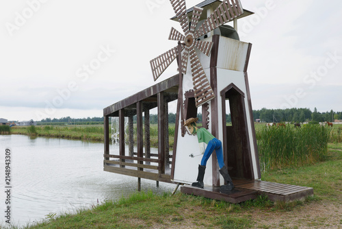 Konstfotografi Decorative wooden windmill structure standing by countryside pond lake