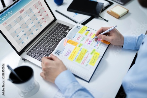 Fotografie Professional planning weekly schedule in planner with laptop computer on white d