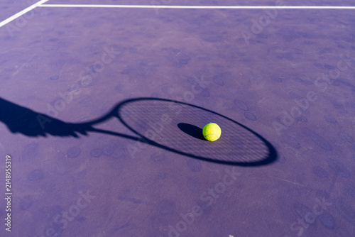 Tennis ball on court with racket shadow